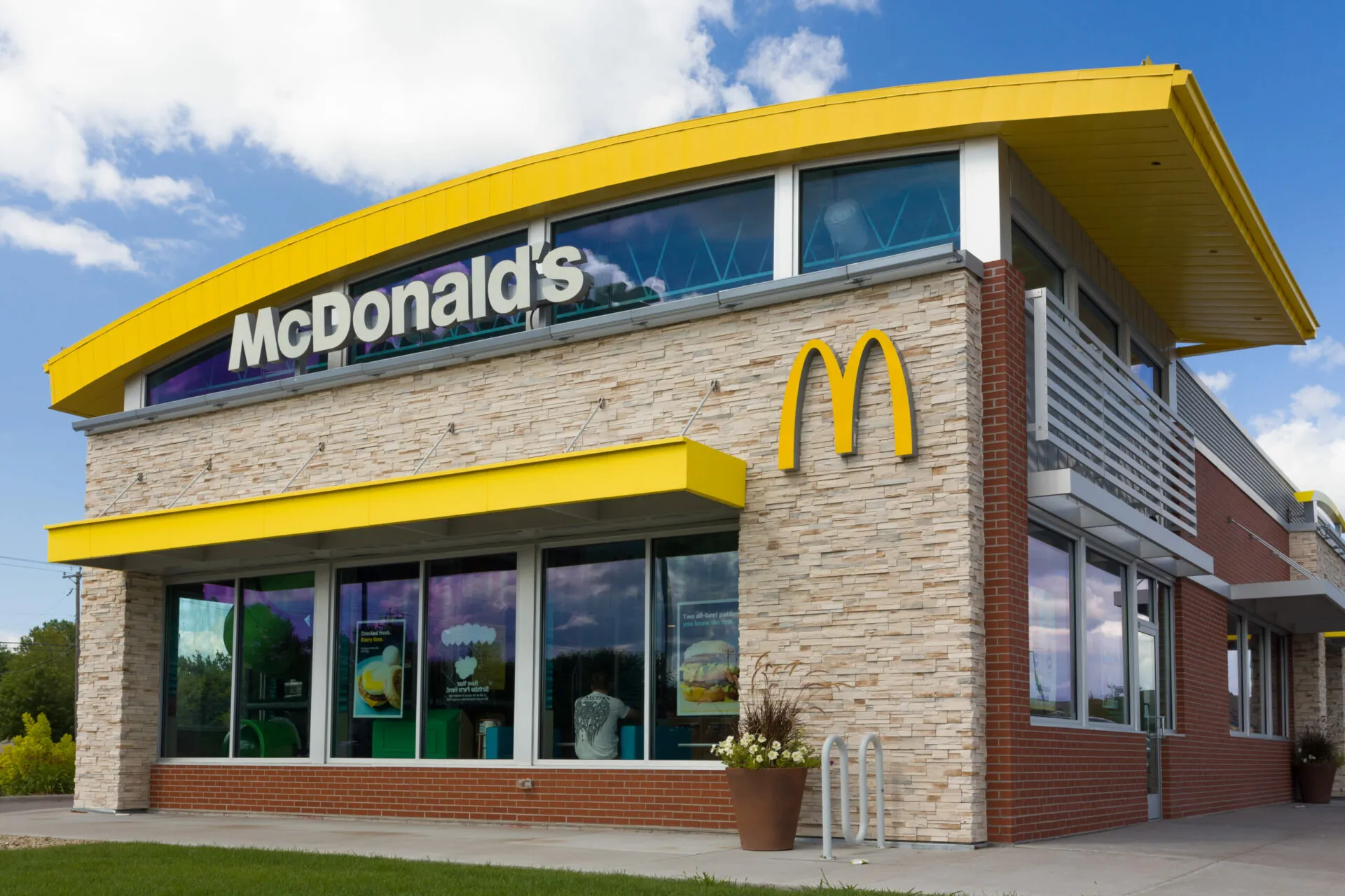A mcdonald 's restaurant with yellow awnings and a blue sky.