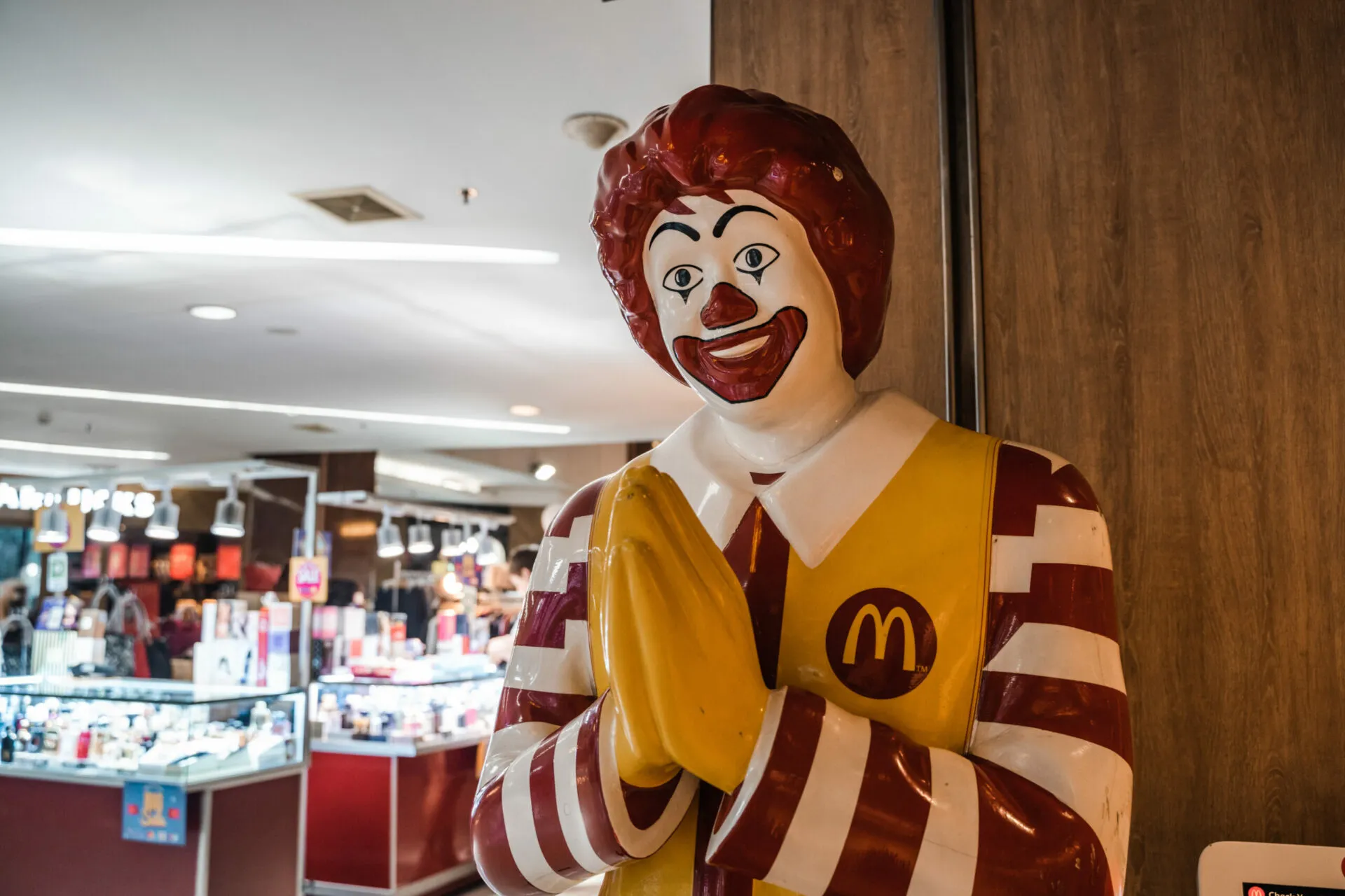 A ronald mcdonald statue in an indoor mall.